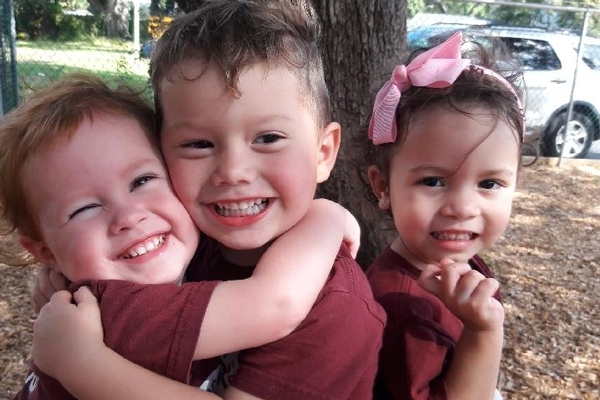 preschool students hugging on playground