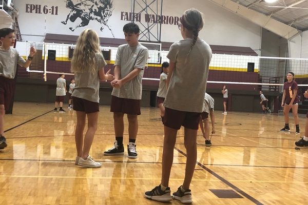 bcs middle students work on volleyball skills in the gym